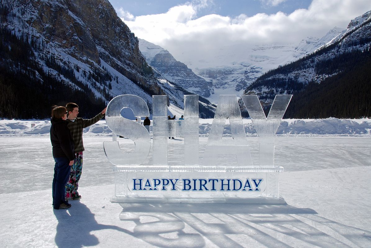 19 Charlotte Ryan and Peter Ryan With Happy Birthday Shay Ice Sculpture On Frozen Lake Louise With Mount Victoria Behind